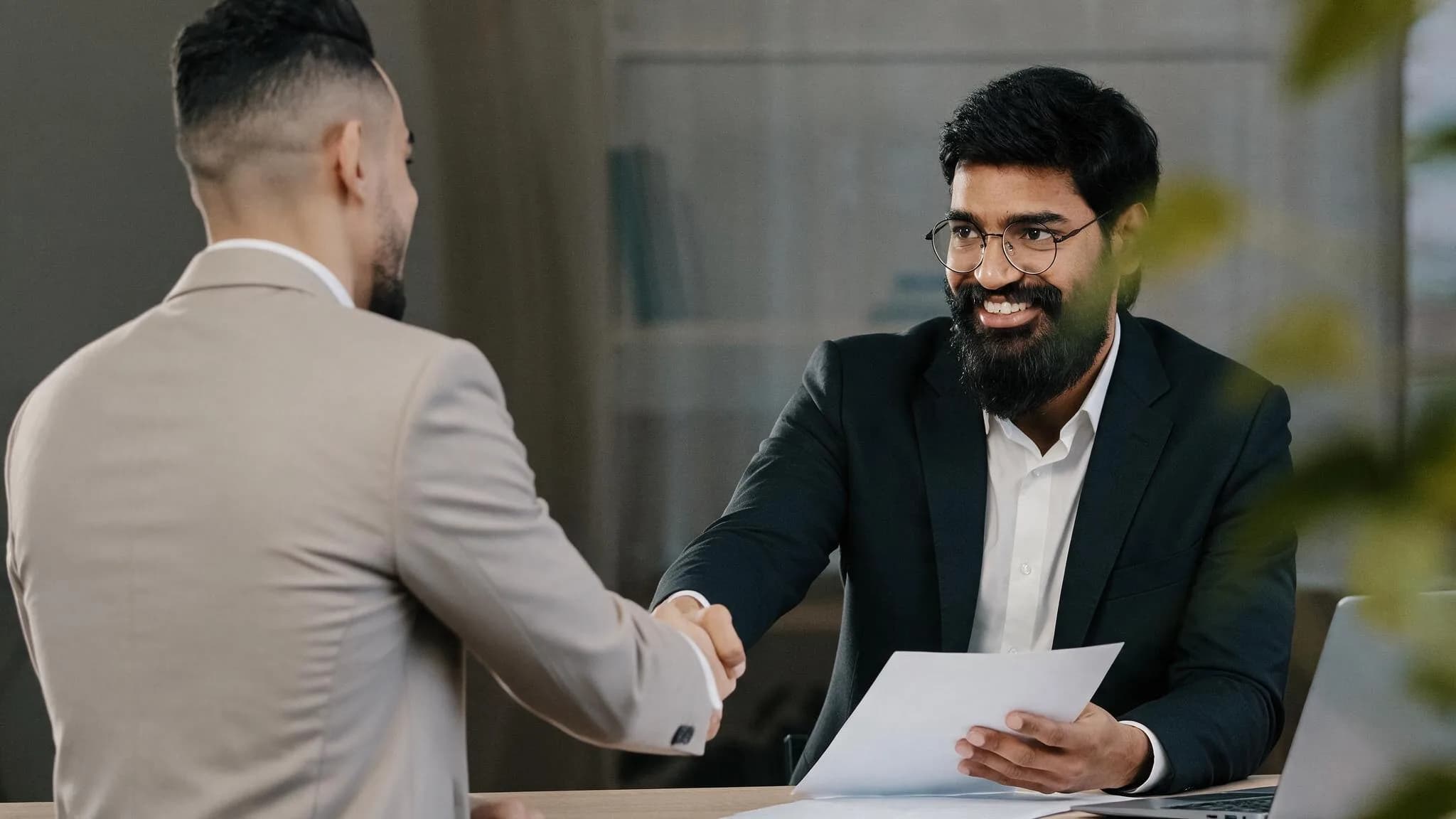 Two professionals shaking hands over project documents