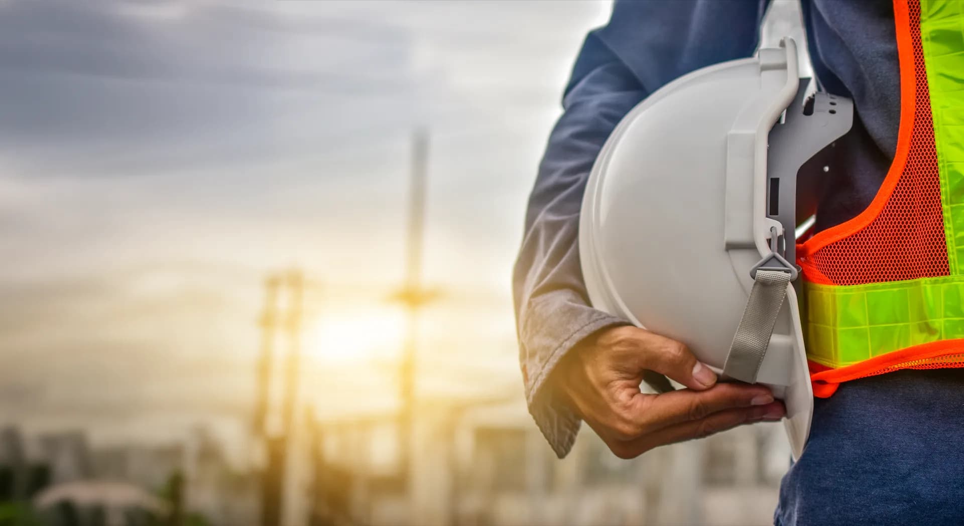 Construction worker in high-visibility gear holding a hard hat