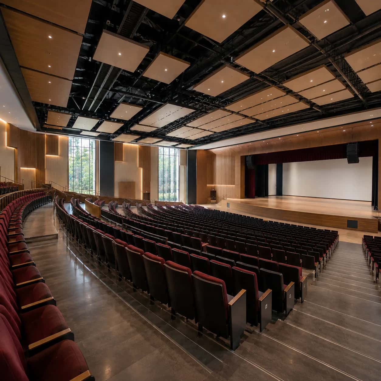 Interior of a school and college auditorium with red seating and a wooden stage